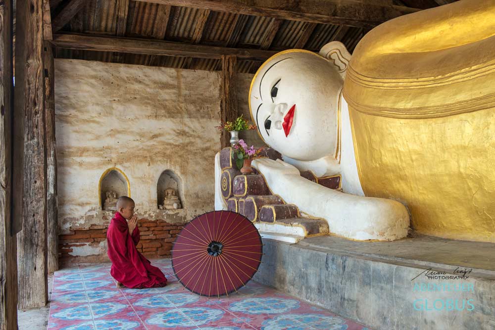 Gebet vor einem liegenden Buddha: Fotoserie Der Rote Schirm aus Südostasien, Fotograf Mario Weigt