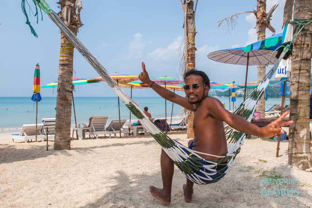 Mann vermietet Strandliegen und Sonnenschirme am Kamala Beach auf der Insel Phuket